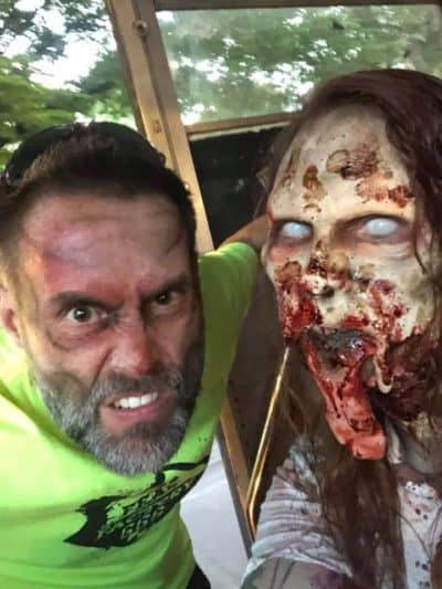 Spencer Terry in haunt makeup shows off a gruesome severed head prop